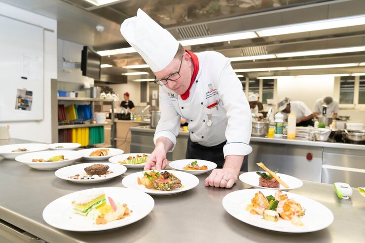 This image shows a chef checking the dishes before serving to guests. The dishes are prepared with elements from different cultures.